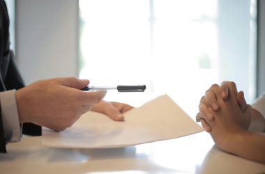 Close-up of a contract signing with hands over documents. Professional business interaction.
